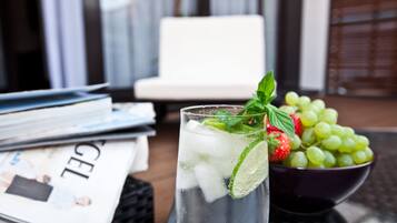 Ein Glas gekühltes Getränk mit Minze und Limette, eine Schüssel mit grünen Trauben und eine Zeitschrift auf einem Tisch.