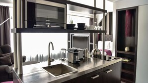 Una cucina moderna con forno a microonde, tostapane e bollitore integrati, un lavandino e una finestra con tende.