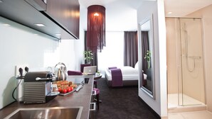 Una moderna camera d'hotel con angolo cottura, un letto con vista e cabina doccia.