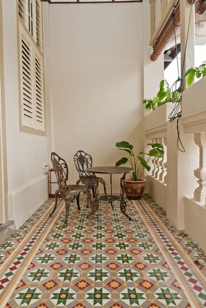 Un pequeño patio amurallado con suelo de baldosas, una mesa con sillas y una planta en maceta.