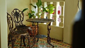A small, ornate table with intricate metalwork, accompanied by matching chairs, set on a colorful tiled floor. - PalanquInn Heritage Suites (George Town)