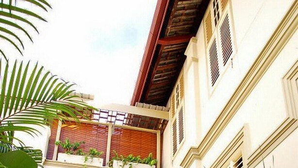 A courtyard with a pathway, potted plants, and a building with a balcony. - PalanquInn Heritage Suites (George Town)