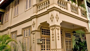 A two-story building with a balcony, large windows, and a well-maintained garden. - PalanquInn Heritage Suites (George Town)