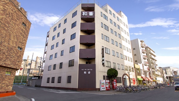 A multi-story building with a sign indicating it is a hotel. - Business Hotel Wako (Osaka)