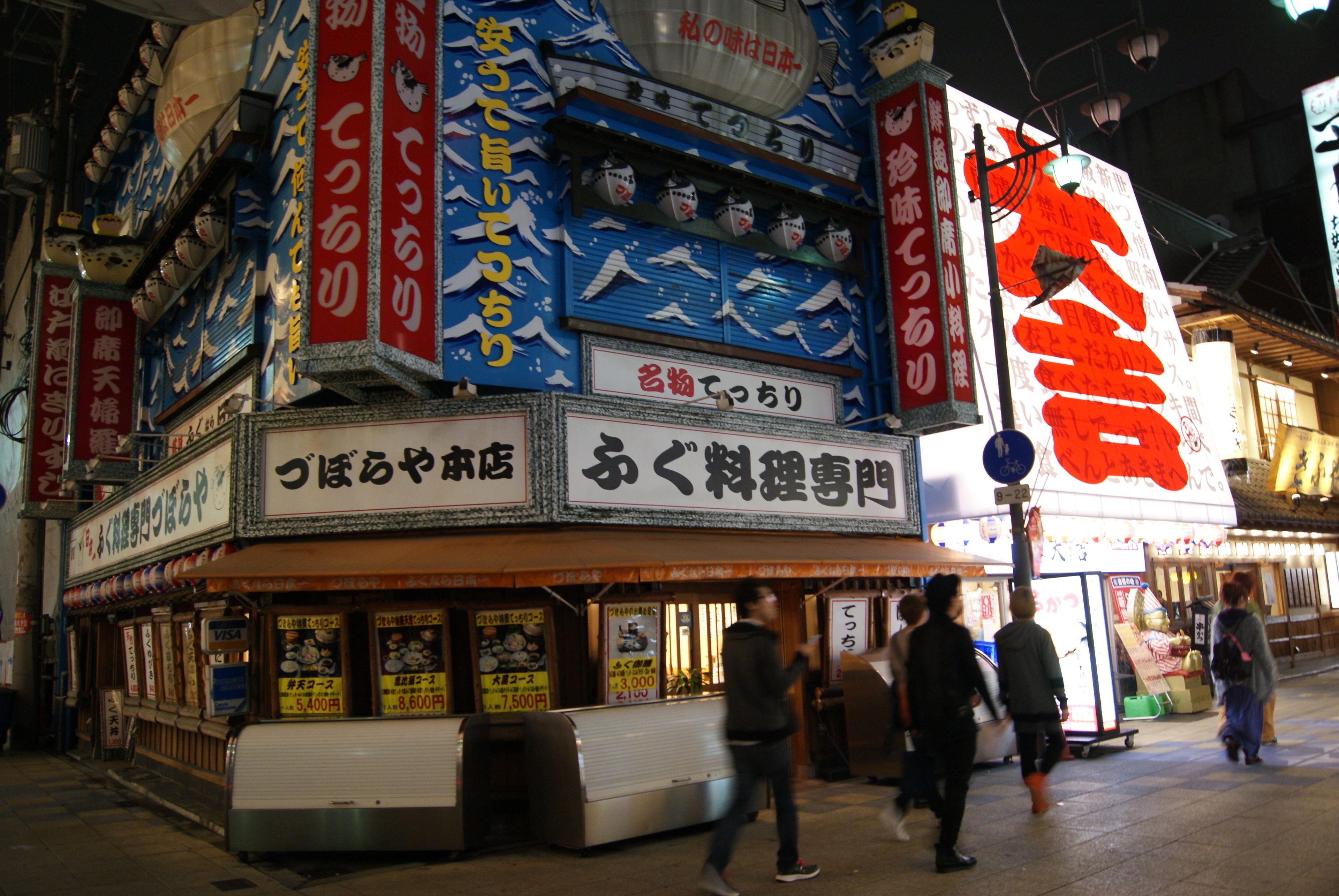 A traditional Japanese building with multiple signs and a storefront.