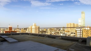 A rooftop terrace with a view of a city skyline, including a tall building and several other structures. - Business Hotel Wako (Osaka)