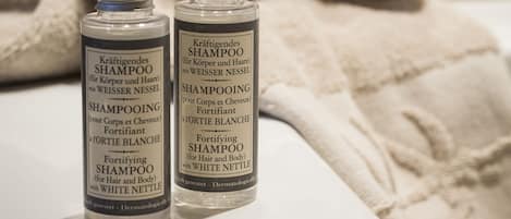 Two bottles of shampoo and a wooden coaster on a white surface.