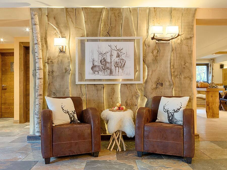 Una habitación con dos sillones de cuero, una pared de madera con una ilustración enmarcada de un ciervo y una pequeña mesa con fruta.