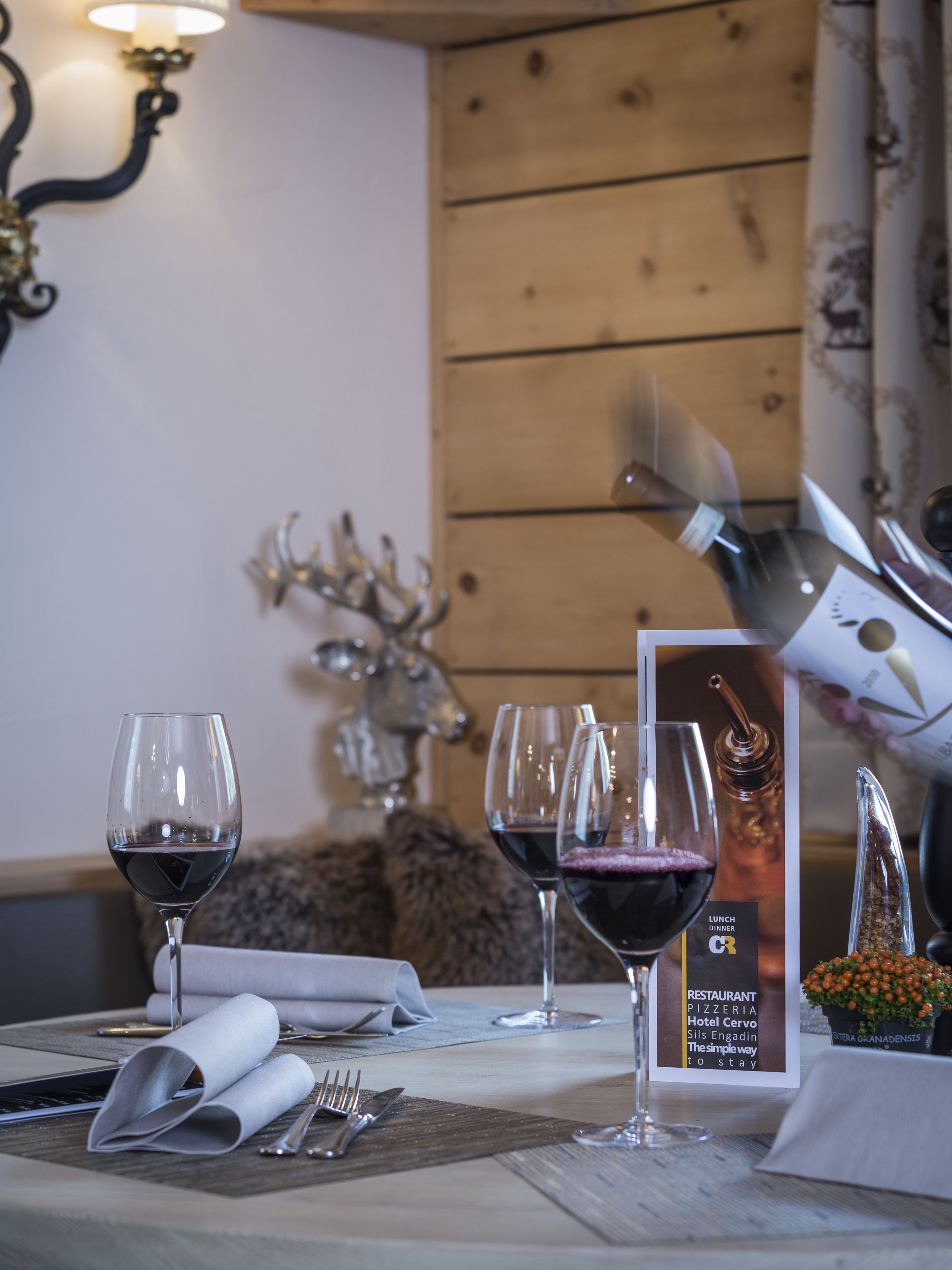 A dining table set with wine glasses, cutlery, and a menu.