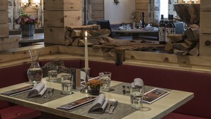 Un interior de madera con una mesa de comedor preparada para dos, una vela y un espejo que refleja la habitación.