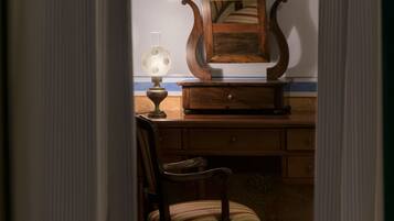 A room with a wooden desk, a chair, a lamp, and a framed certificate on the wall.