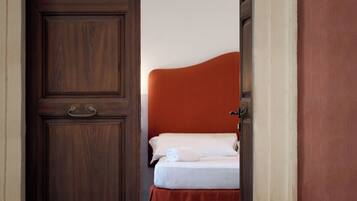 Een hotelkamer met een houten deur, een bed met een rode hoofdeinde en een wit sprei.