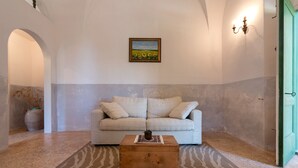 A living room with a sofa, a wooden coffee table, a painting, and a vase with dried plants. - Palazzo Laura (Morciano di Leuca)