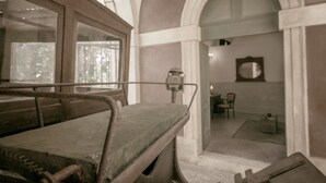 A room with a large bed, a wooden headboard, a window, and a door leading to another room. - Palazzo Laura (Morciano di Leuca)