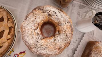 A table with a bundt cake and a pie on a lace tablecloth.