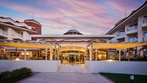 A hotel entrance with a covered walkway, a central dome structure, and multiple balconies.