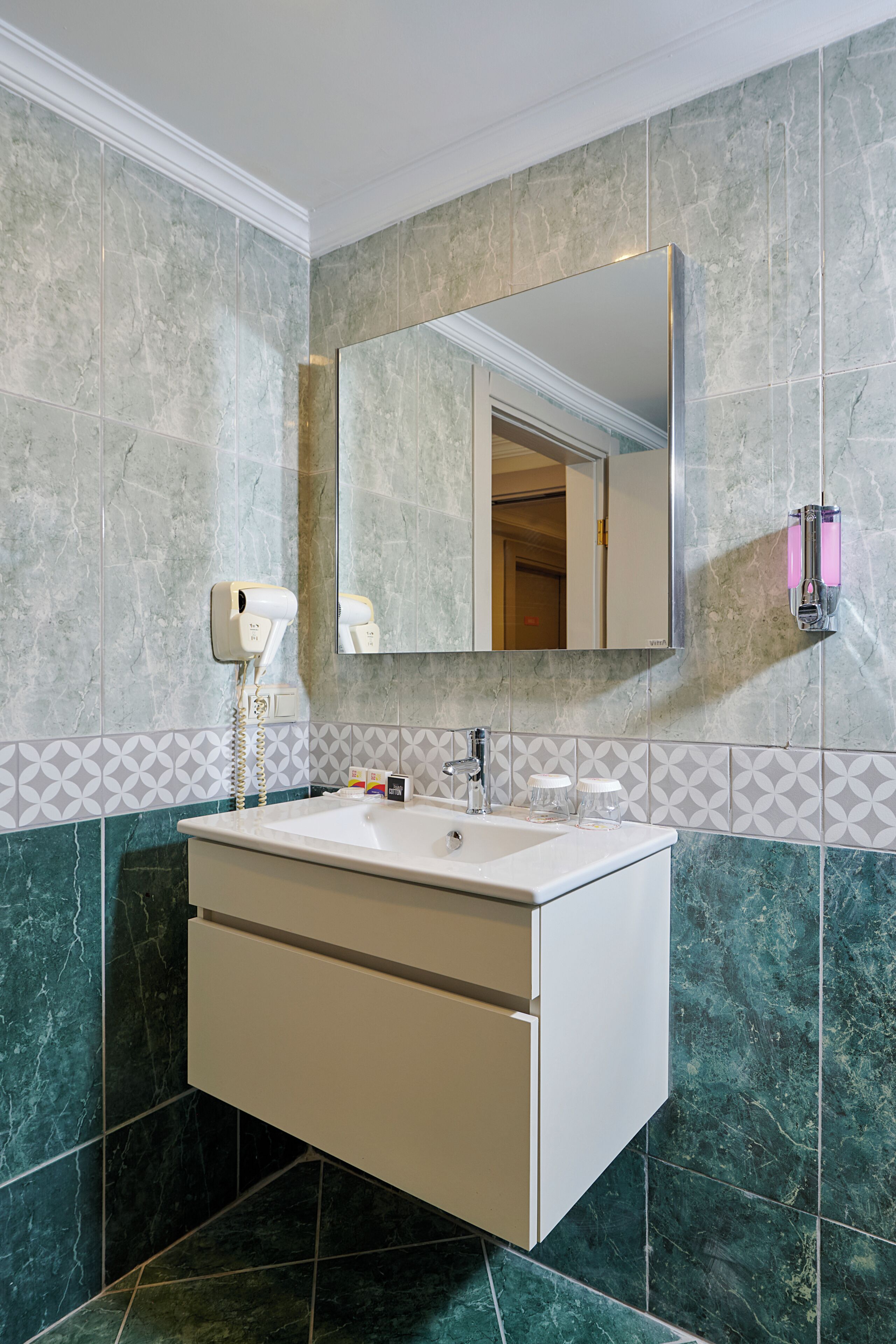A bathroom with a white vanity, a mirror, and a hairdryer.