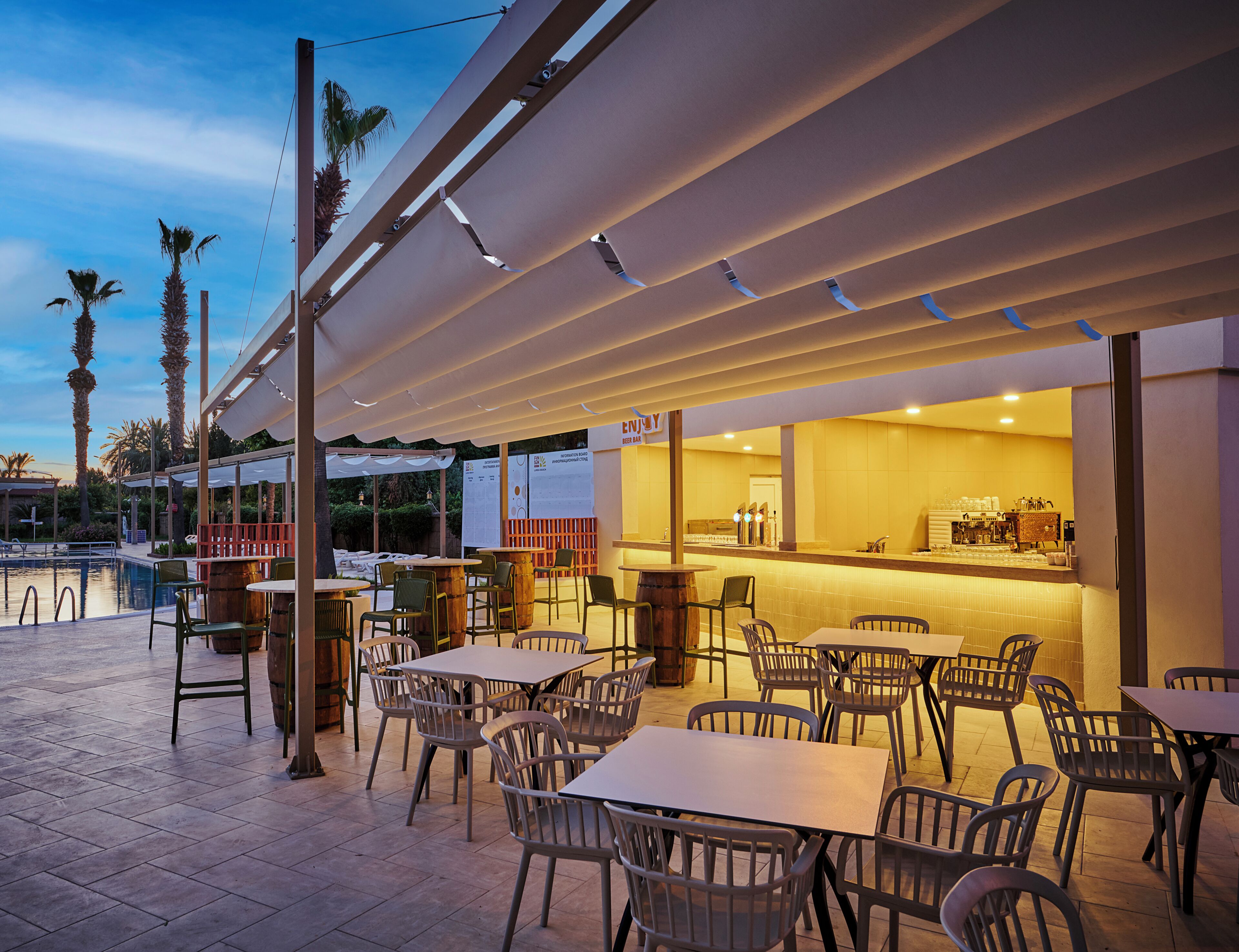 An outdoor seating area with tables and chairs, a pool, and a bar.