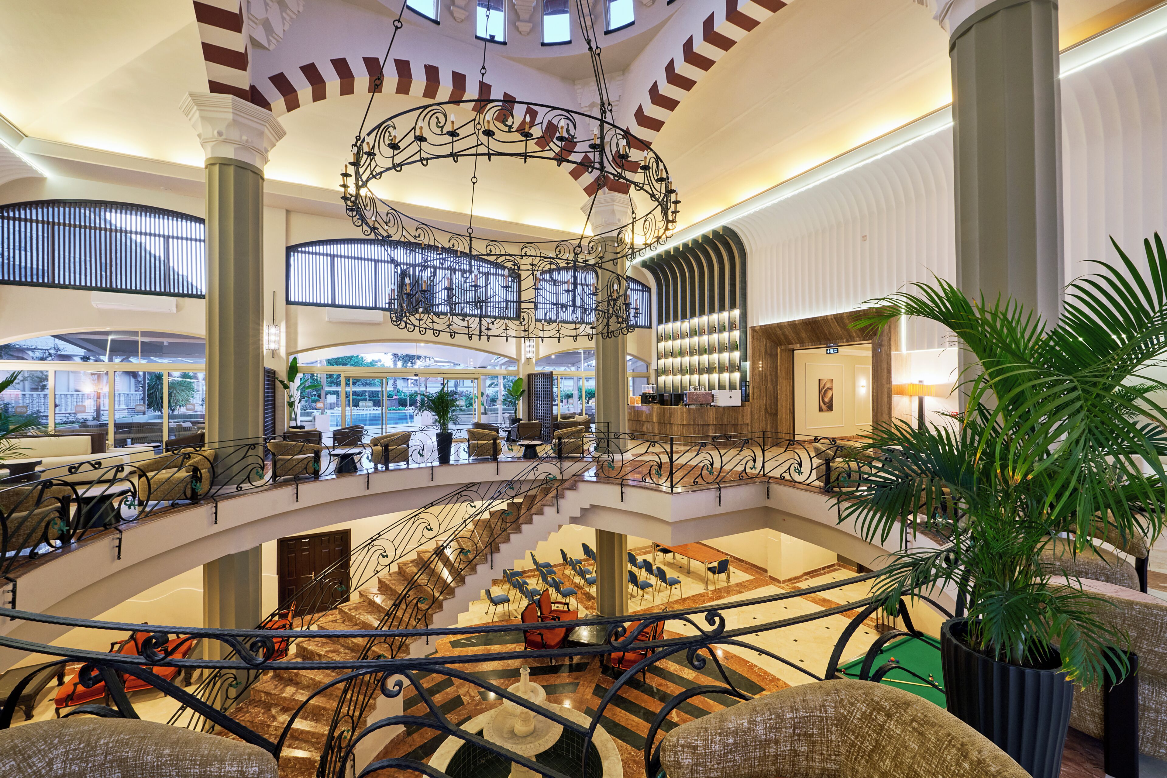A spacious lobby with a central fountain, multiple seating areas, and a pool table.
