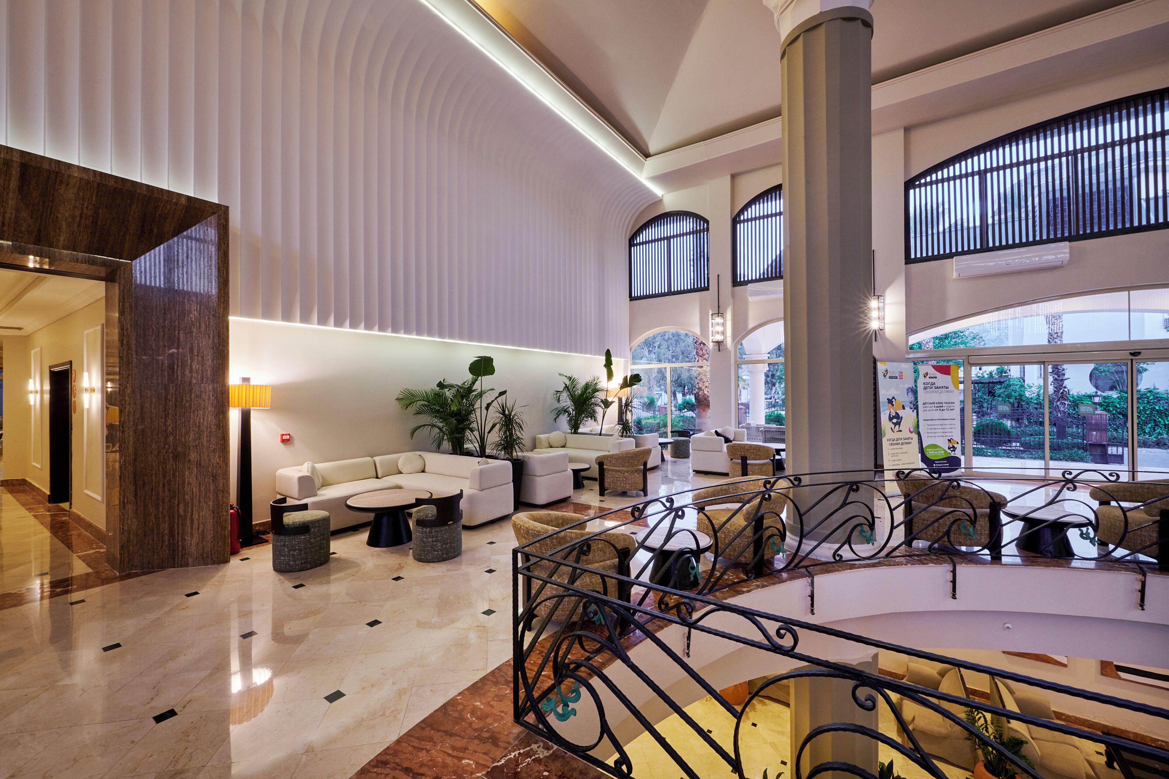 A spacious lobby with a high ceiling, a central seating area, and large windows.
