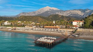 A beach resort with a pier, lounge chairs, and a mountain backdrop. - Fun Sun Smart Akman Beach - All inclusive (Kemer)