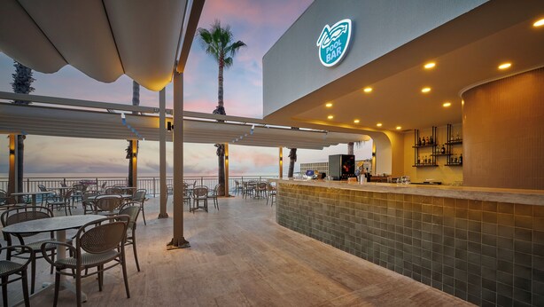 An outdoor bar area with a pool bar, tables, chairs, and a view of the ocean. - Fun Sun Smart Akman Beach - All inclusive (Kemer)