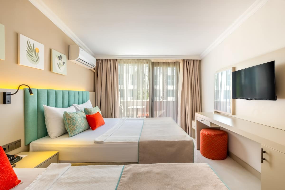 Une chambre d’hôtel avec deux lits, une télévision et une fenêtre avec des rideaux.