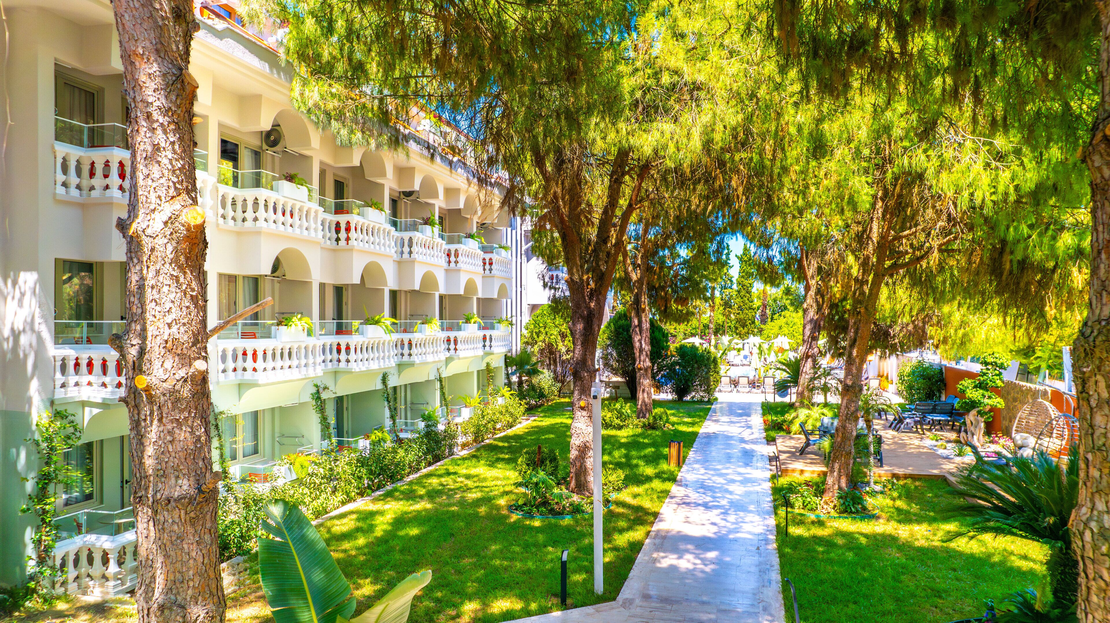 Un hôtel doté de nombreux balcons, d’un jardin bien entretenu et d’un chemin menant à l’entrée.