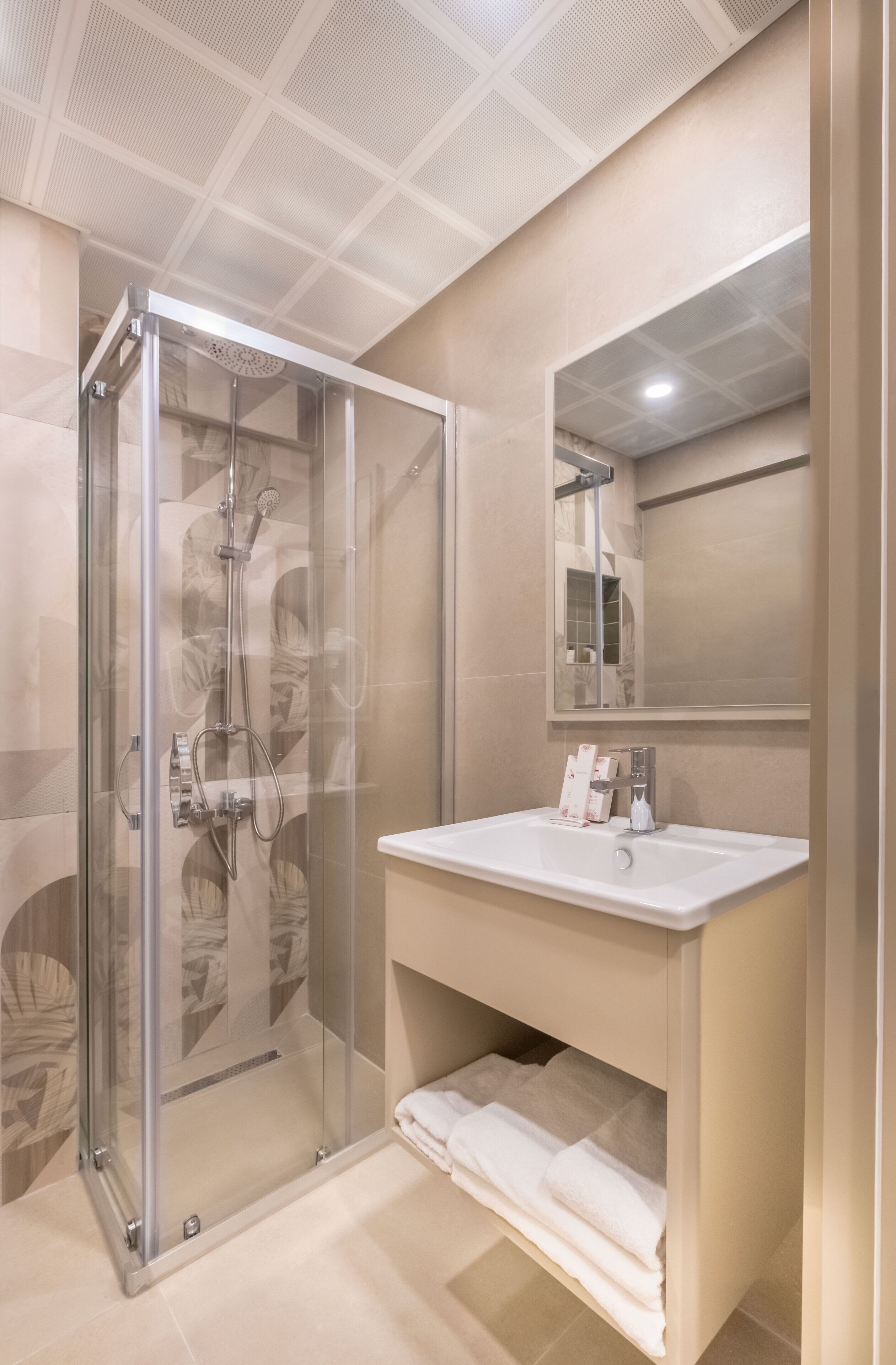 Een moderne badkamer met een douchecabine van glas, een wastafel met spiegel en een handdoekrek.