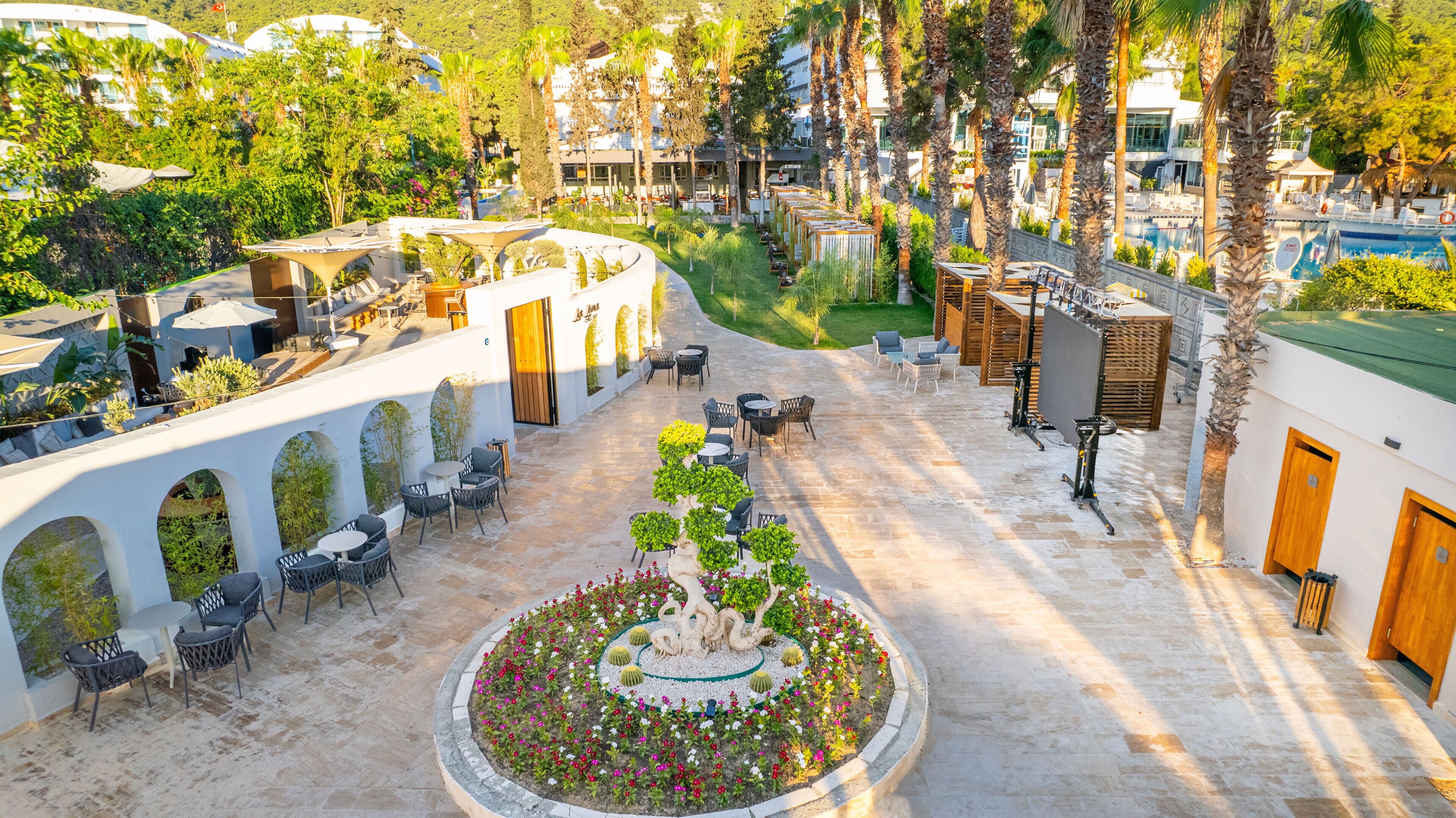 Un patio al aire libre con mobiliario y un jardín central.