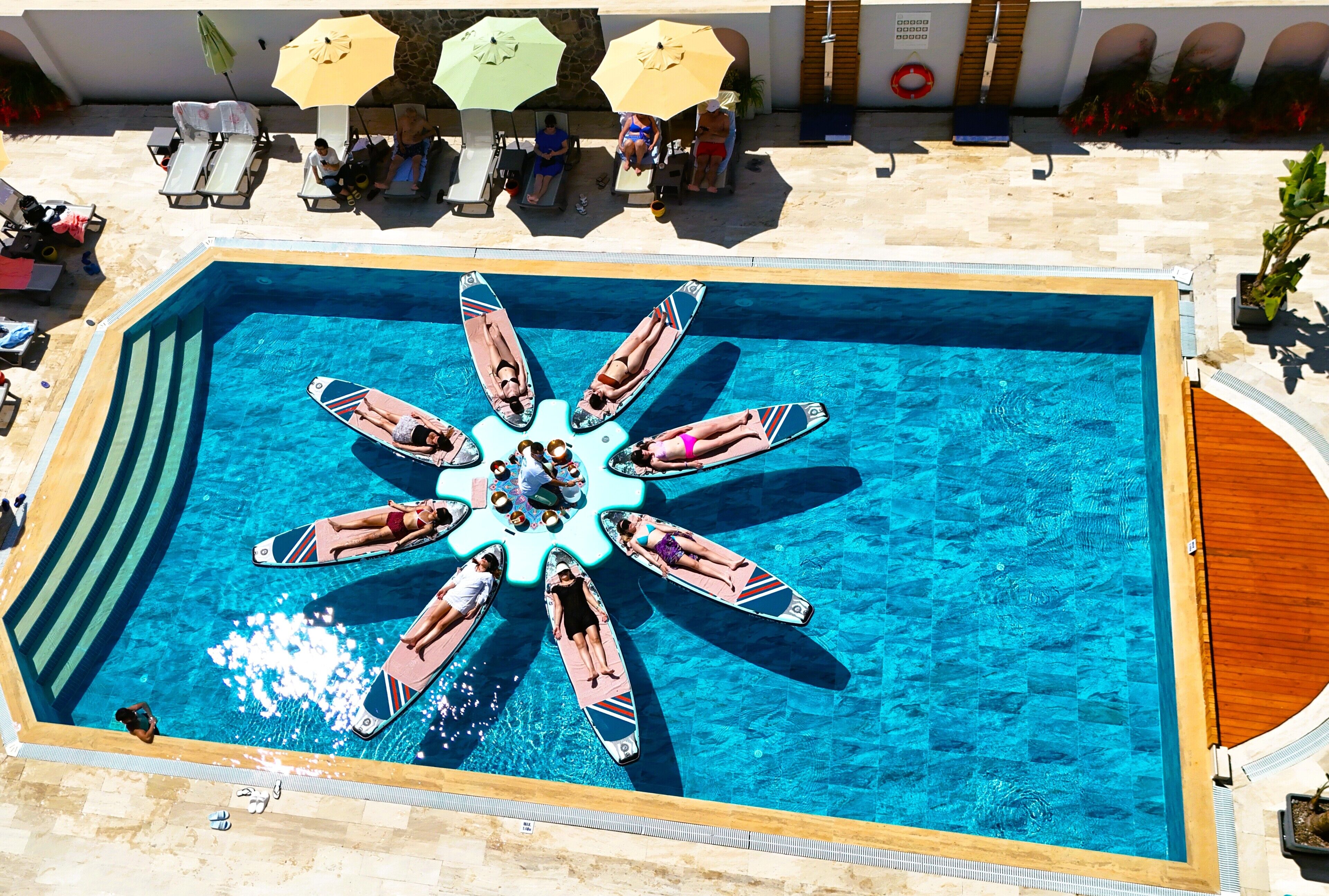Una piscina rectangular con una isla central y tumbonas alrededor.