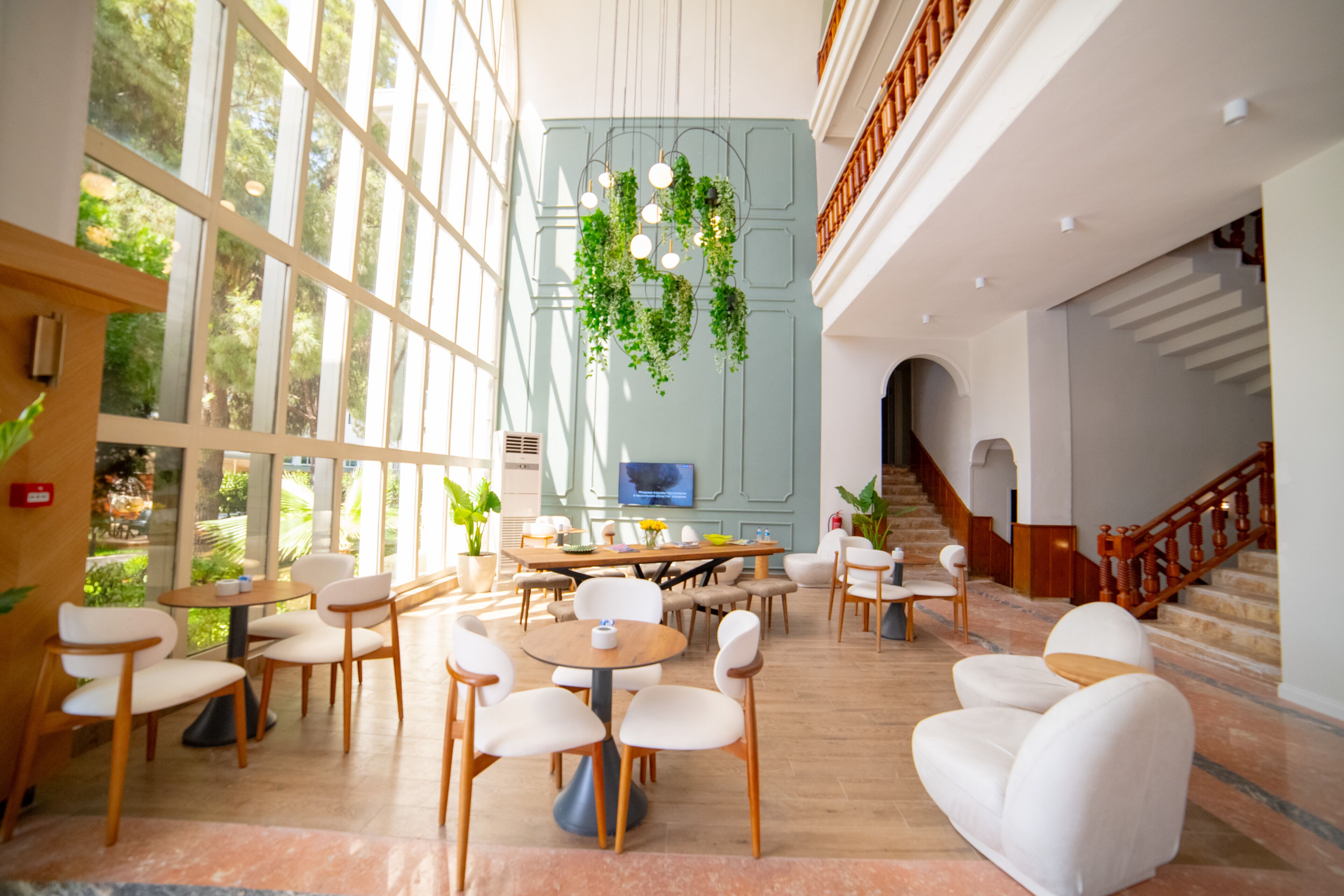 A spacious lobby with large windows, a central seating area, and a staircase.