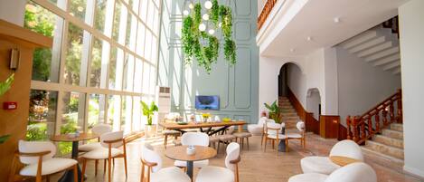 A spacious lobby with large windows, a central seating area, and a staircase.
