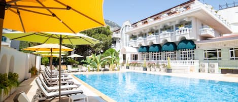 Relax by the inviting pool, surrounded by lush greenery and comfortable sun loungers.