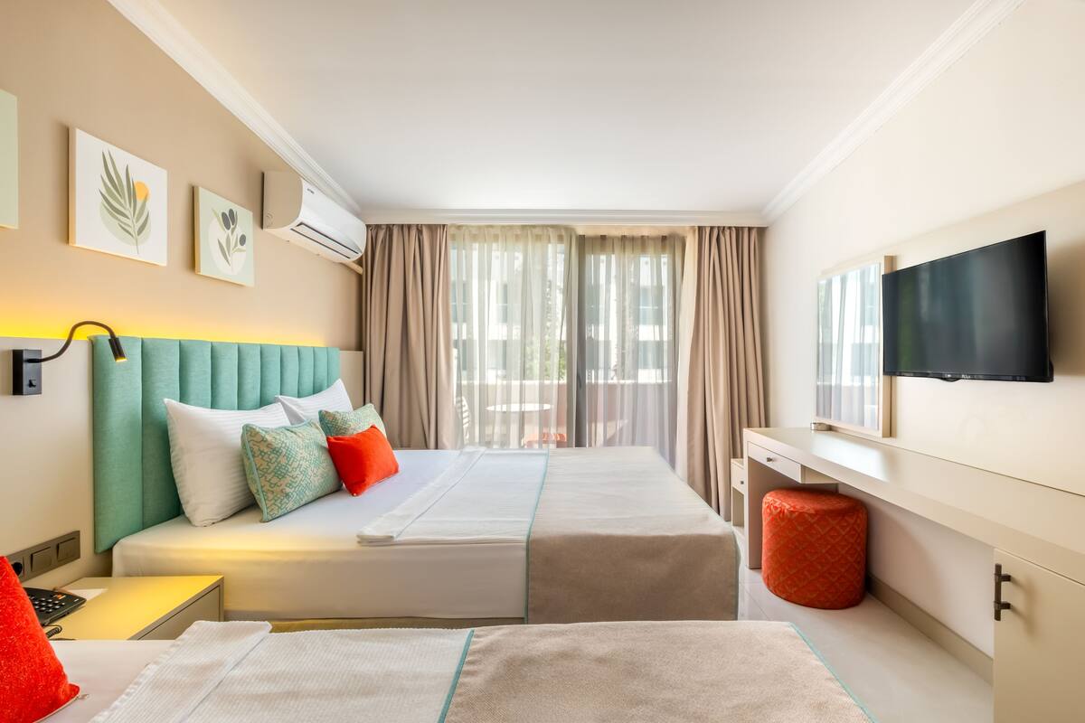 Une chambre d’hôtel avec deux lits, une télévision et une fenêtre avec des rideaux.