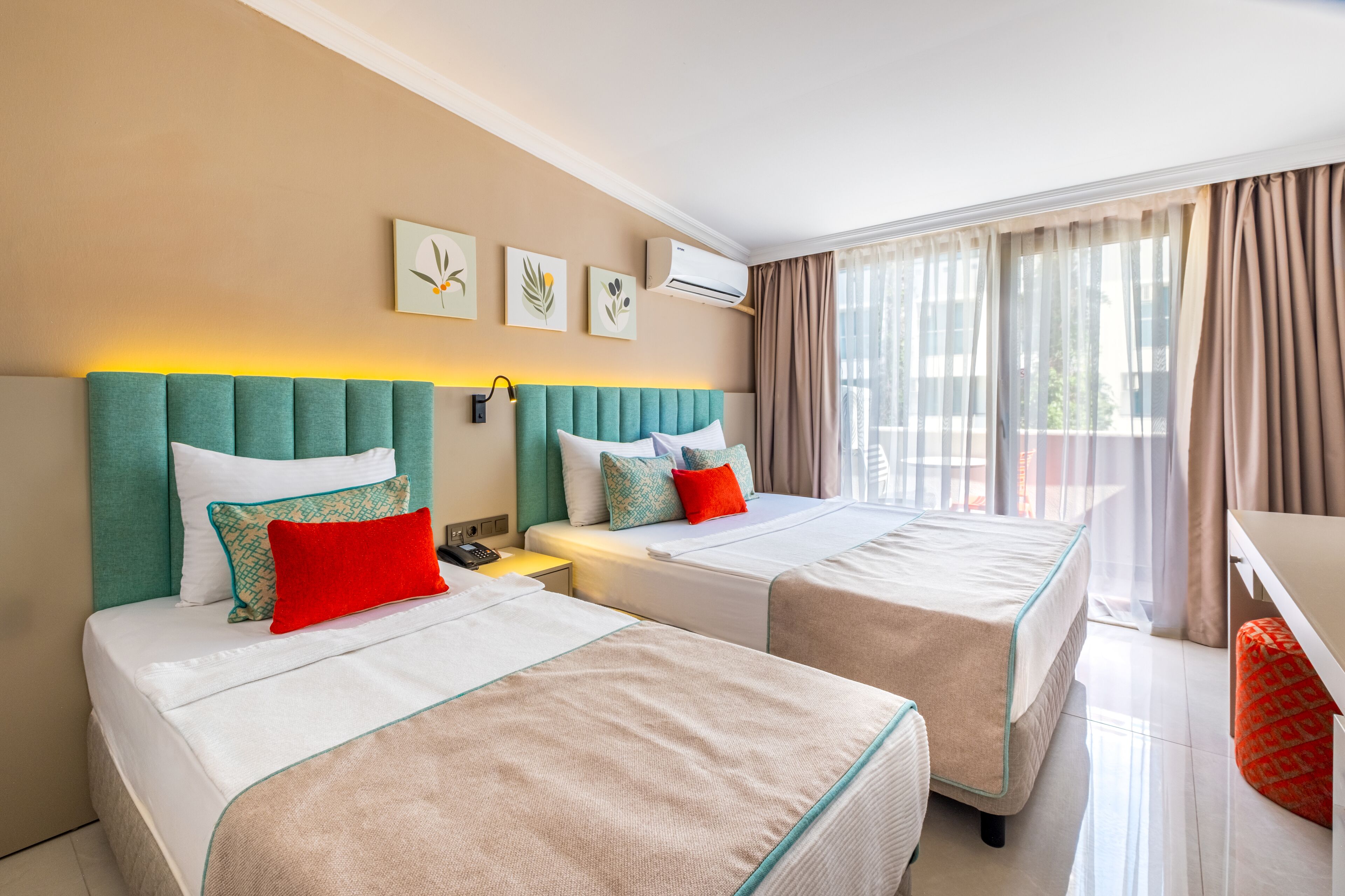 Habitación de hotel con dos camas, un escritorio y una ventana con cortinas.