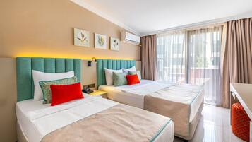 Habitación de hotel con dos camas, un escritorio y una ventana con cortinas.