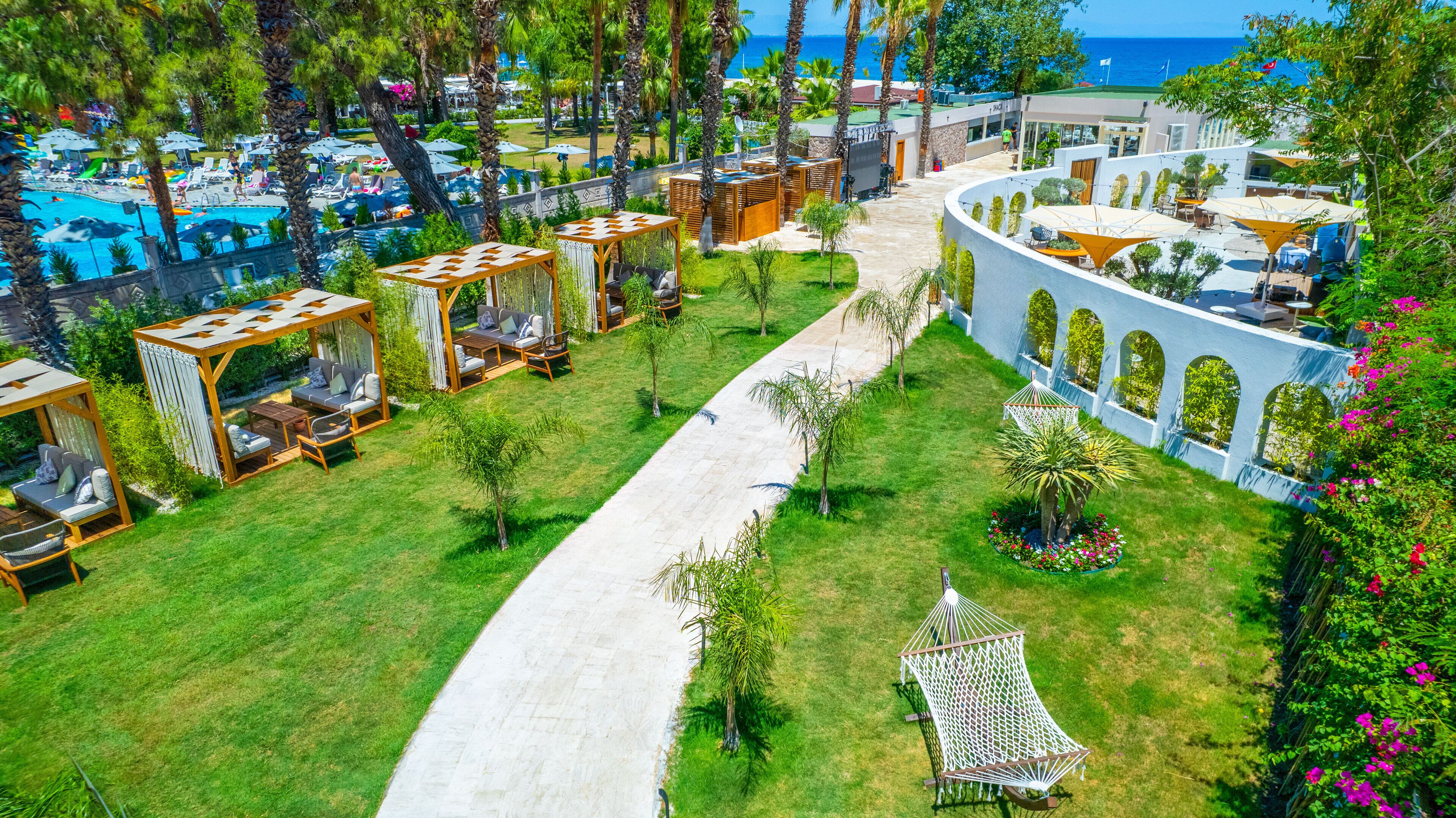 Vista aérea de un resort con piscina, zonas de estar al aire libre y un camino.