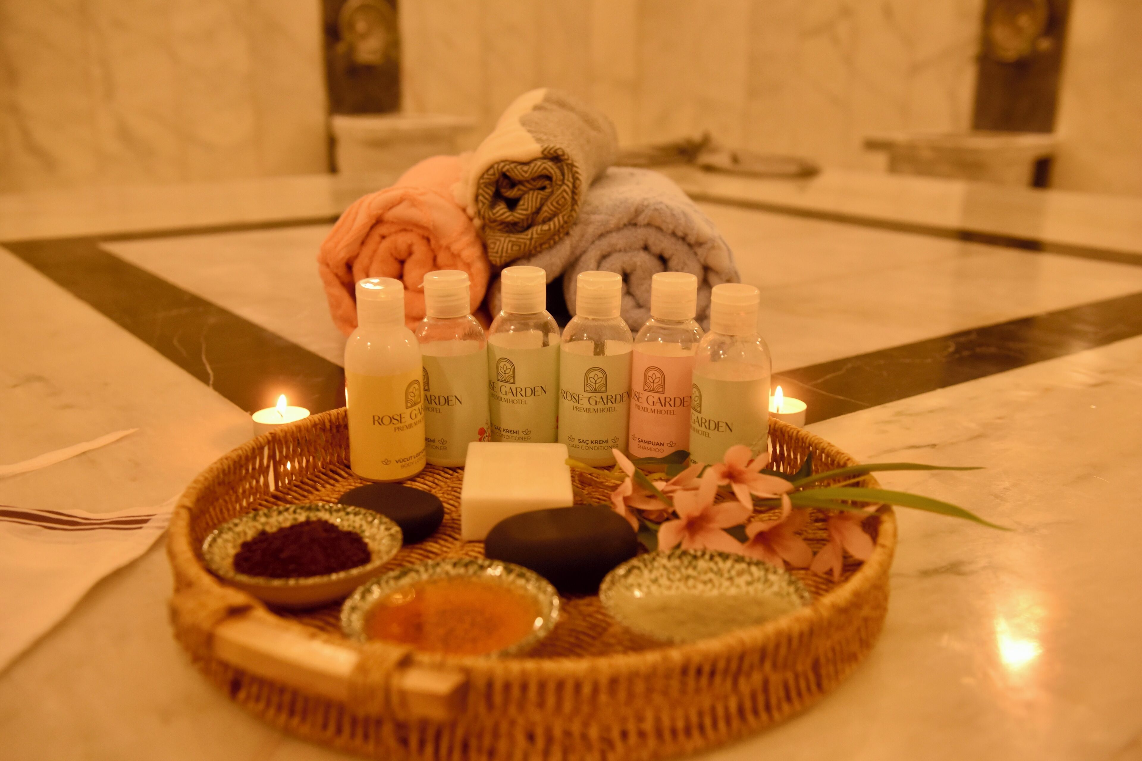 Un ambiente de spa con una bandeja de productos de baño, velas y toallas.