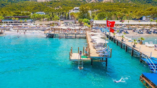 Un resort costero con un muelle, sombrillas de playa y sillones de descanso.