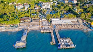 Vista aérea de un complejo turístico costero con varios muelles, servicios en la playa y una variedad de edificios, incluyendo hoteles y restaurantes.