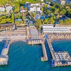Experience the resort's stunning coastal setting, featuring a hotel with a modern design, a well-organized beach area, pool, and pier.