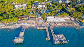 Vista aérea de un complejo turístico costero con varios muelles, servicios en la playa y una variedad de edificios, incluyendo hoteles y restaurantes.
