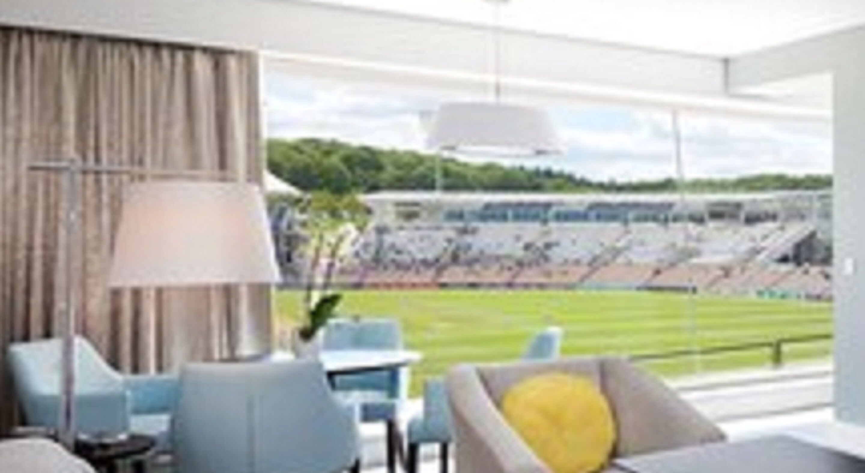 Hotellihuone, jossa on suuri ikkuna, josta avautuu näkymä stadionille.
