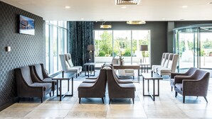 A modern lobby with a checkered wall, a large window, and a seating area with sofas and tables.