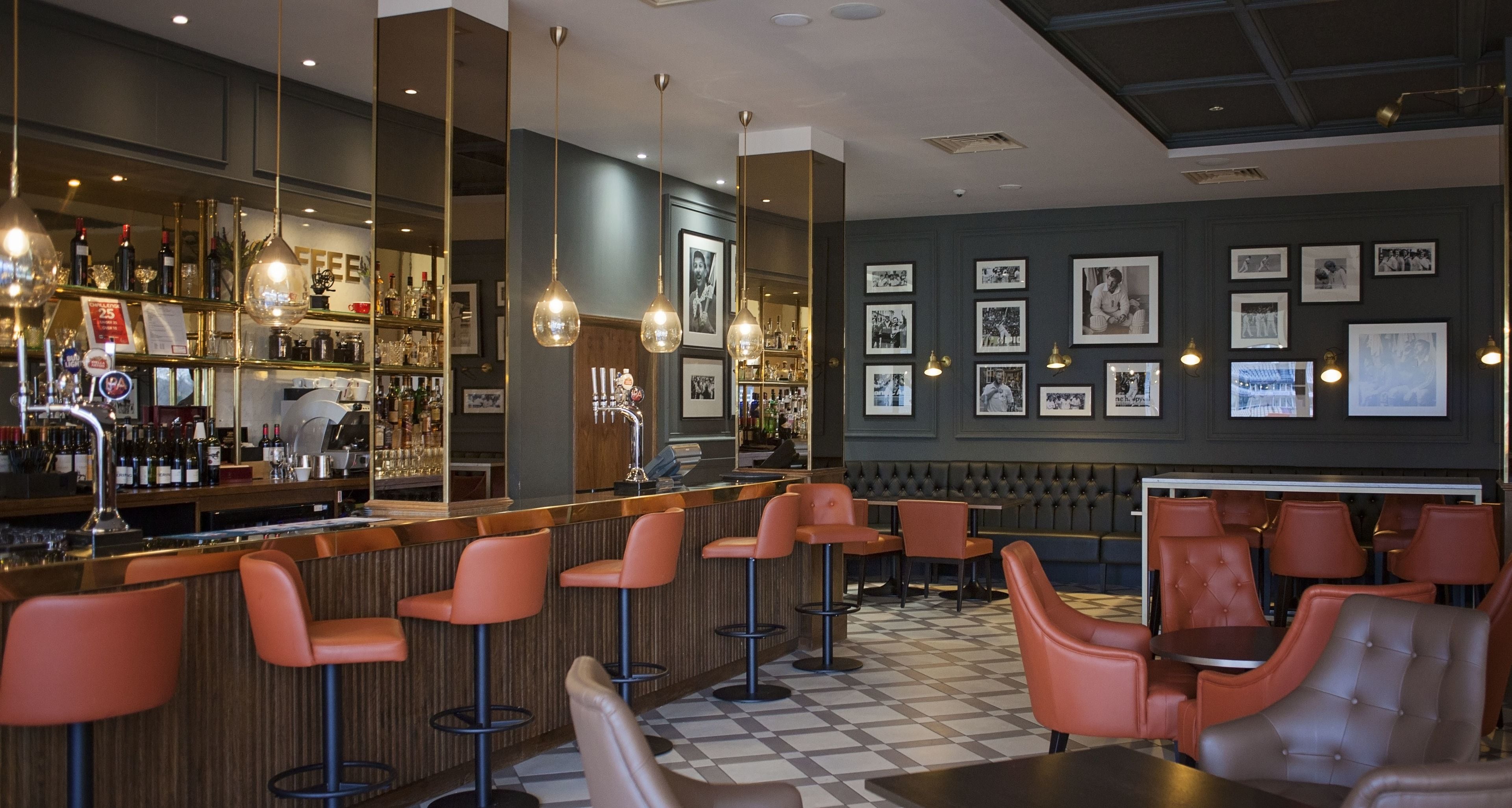 A bar area with a checkered floor, bar stools, and a variety of bottles and glasses on shelves.