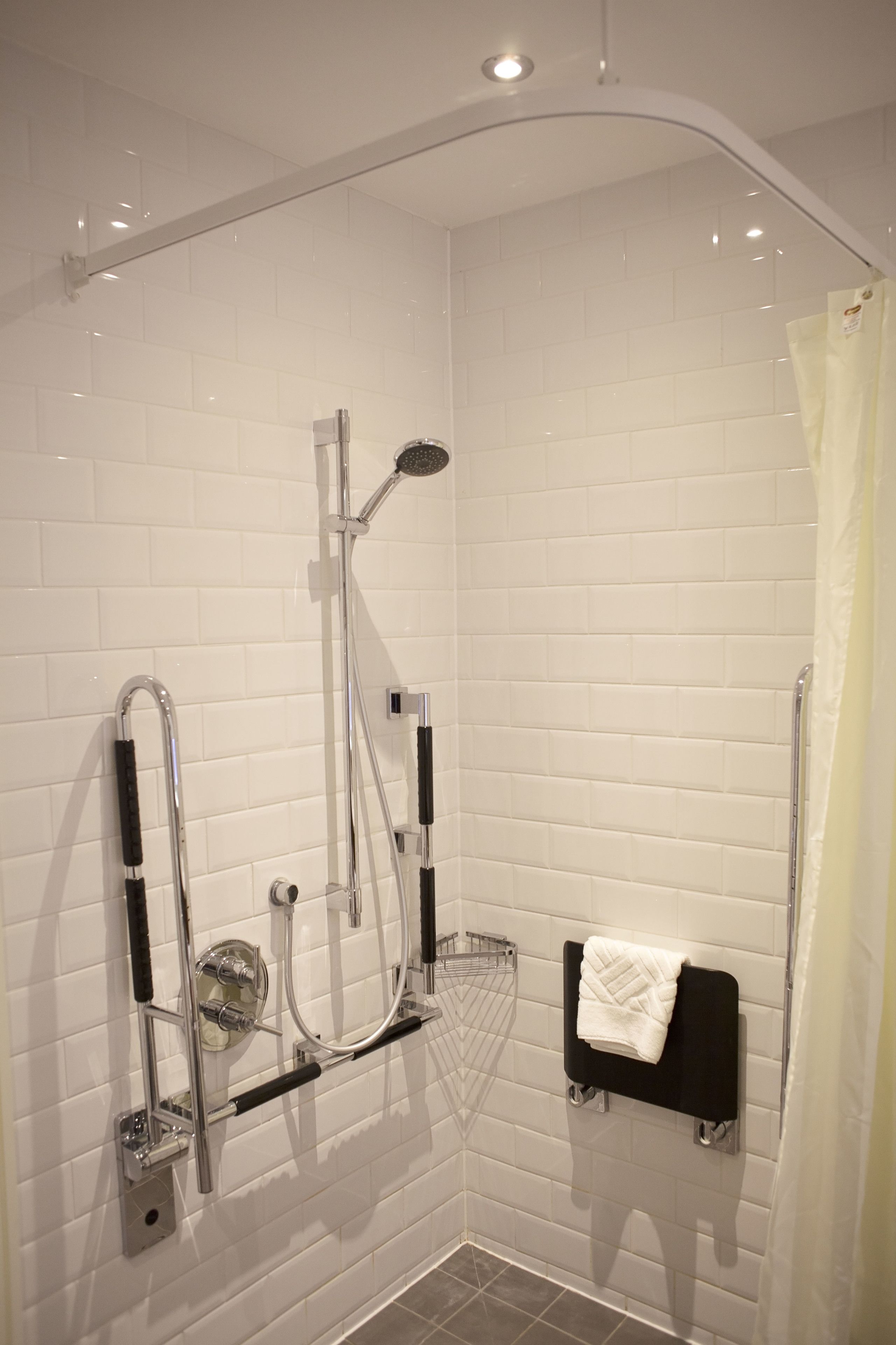 A modern shower with a handheld showerhead, a wall-mounted faucet, and a towel rack with a towel.