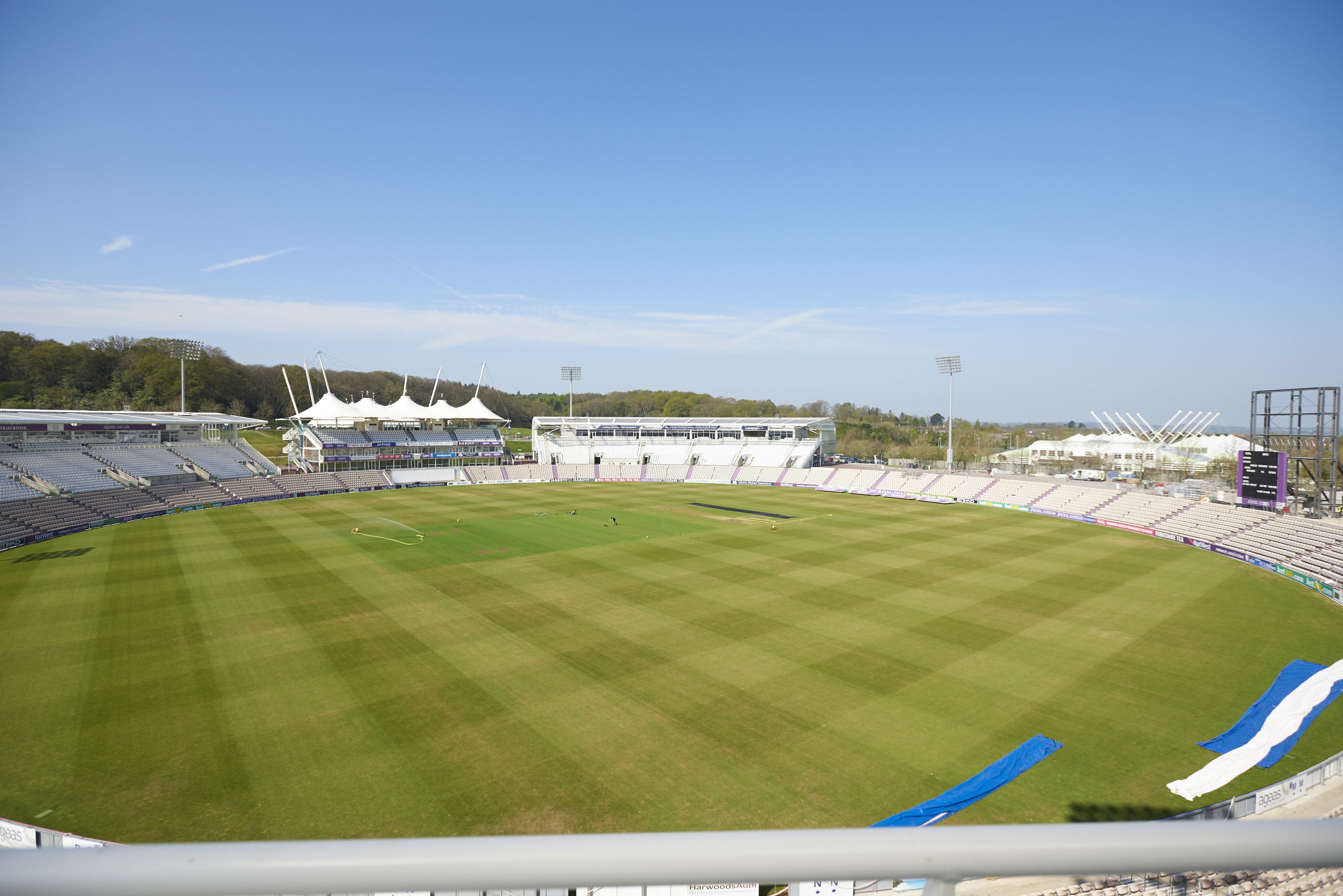 A large, empty stadium with a well-maintained grass field, seating areas, and floodlights.