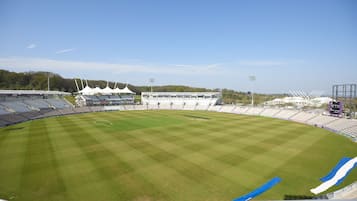 A large, empty stadium with a well-maintained grass field, seating areas, and floodlights.
