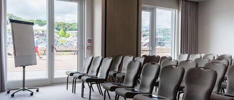 A conference room with rows of chairs, large windows, and a whiteboard.